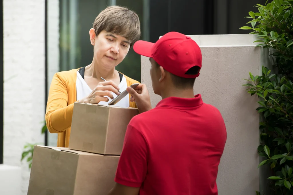 Doha Movers Packers asian delivery man red uniform delivering parcel box woman recipient home with recipient sign receive package smart device scaled 1